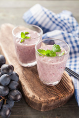 milkshake with banana and grapes in a glass on a table, selective focus