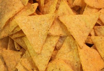 background of yellow tortillas chips with a lot of salt