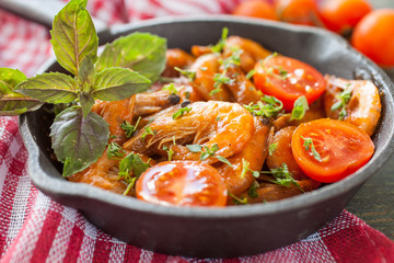 shrimps in tomato sauce with greens on a table, selective focus