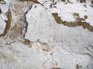 The old plastered background on a building wall with cracks and chips