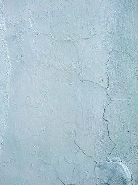 The old plastered background on a building wall with cracks and chips