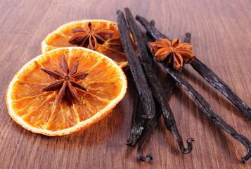 Fragrant vanilla, star anise and dried orange on wooden surface plank