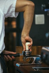 Barista pressing ground coffee with tamper