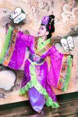 beautiful Chinese woman in traditional dress stands with fans spread her hands apart