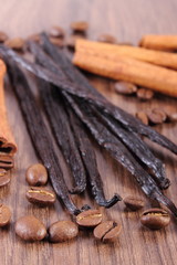 Fragrant vanilla, cinnamon sticks and coffee grains on wooden surface