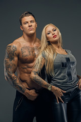 Shirtless brutal tattooed male and sensual blonde female isolate