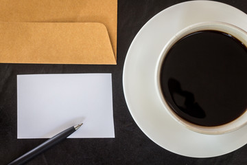 Business card and coffee cup on black background