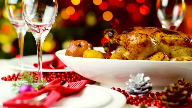 roasted chicken on christmas table in front of fireplace and tree with lights
