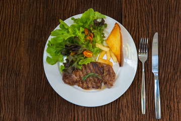 steak beef on white plate on wood background.