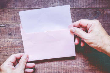 Obraz premium Hand hold a envelope and paper on the wooden background