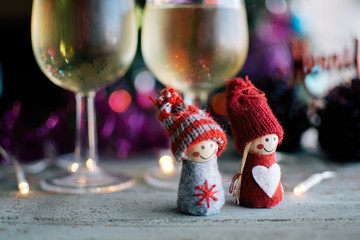 glasses of white wine and knitted dolls with Christmas decoration