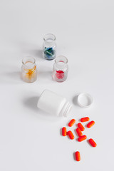 colored pills in glass bottles on white background