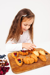 Little girl stuff cakes with fresh berries. Young lassie cooking sweet treat for family. Homemade...