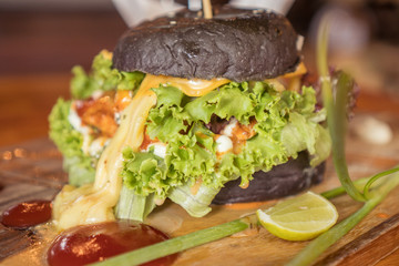 Closeup of beautifully served black burger isolated on wooden cutting board
