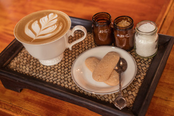 Closeup of beautifully served cup of latte coffee with butter biscuits