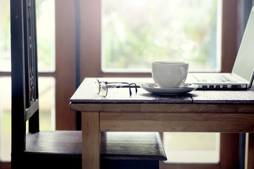 Notebook and cup of coffee on the old wooden table. Simple workspace or in the morning Coffee Break / selected focus.
