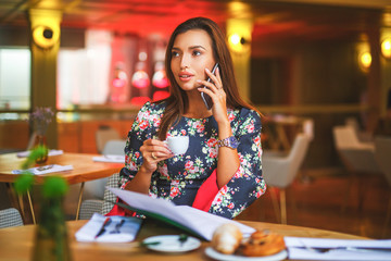 Photo of smiling brunette businesswoman phoning while having breakfast