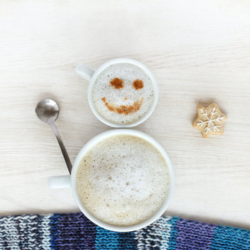 good mood for winter coffee break/ small and large cup of frothy cappuccino standing together in a cheerful snowman top view 