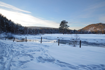 Winter landscape with a stream and snowy shores