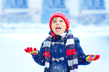 Happy kid boy having fun with snow in winter