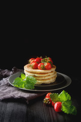 Stack of homemade Pancakes with fresh Wild Strawberries on a pla