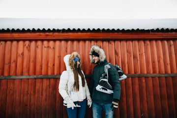 Happy couple in love with skates on a winter day on a background of a wooden house.
