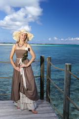 Fototapeta na wymiar The beautiful woman in a long dress on a wooden platform over the sea