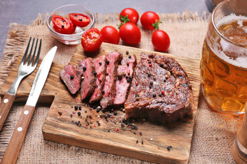 Tasty grilled steak with beer on cutting board