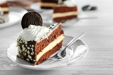 Plate with piece of tasty chocolate cake and fork on wooden table