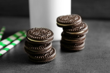Chocolate cookies and straws on dark table, close up view