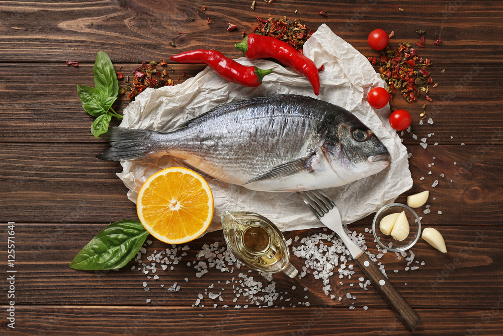 Poster Raw fish with spices on wooden table