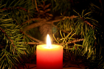 Beautiful Christmas candle with New Yera`s tree brunch on dark background