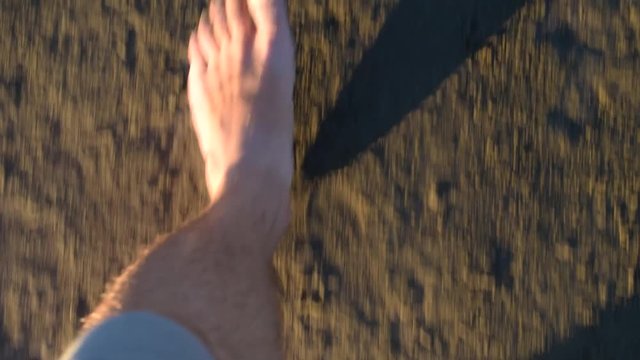 Top view of feet of man walking on wet sand in slow motion