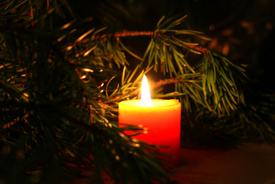 Beautiful Christmas candle with New Yera`s tree brunch on dark background