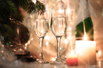 New Years Eve celebration background with an elegant arrangement with a clock counting down to midnight, flutes and bottle of champage and party garland with a cracker, bubble bokeh