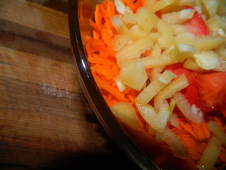 The transparent plate salad of grated carrot, chopped peppers, chopped red tomato