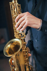 Young man in a suit hold a saxophone musical instrument