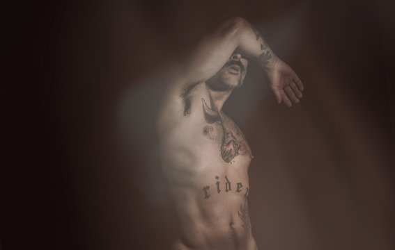 Hombre semidesnudo tap&aacute;ndose la cara.