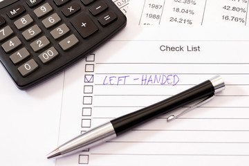 Left-handed ticked position on a check list with pen, calculator