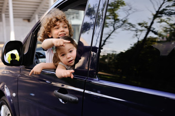 children look out from a car window