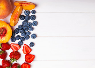 Fototapeta na wymiar Fruits and berries on the white wooden background