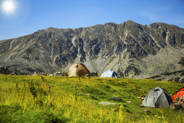 Sunny mountain alpine landscape with camping tents