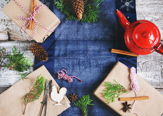 Packing Christmas presents at home. Composition of the boxes, kraft paper, pot, tree branches on a wooden background with a cloth