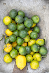 Fresh green Mandarin limes piled with ripe yellow lemons on a rustic wood background in a Turkish village