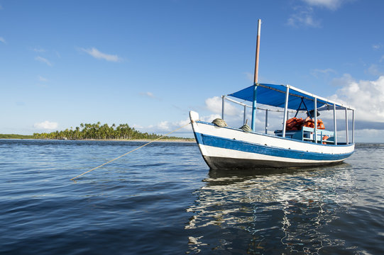 Brazilian fishing boat floating off shore anchored in shallow waters on a remote coast in Bahia, Nordeste Brazil