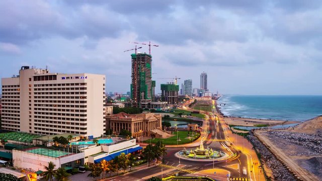Aerial view of Colombo, Sri Lanka modern buildings with coastal promenade area. Time-lapse of car traffic during the night. Sunset sky and ocean waves