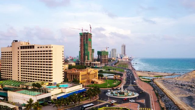 Aerial view of Colombo, Sri Lanka modern buildings with coastal promenade area. Time-lapse of car traffic during the evening. Cloudy sky and ocean waves