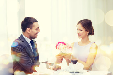 Obraz na płótnie Canvas smiling man giving flower bouquet at restaurant