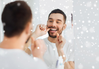 man with dental floss cleaning teeth at bathroom