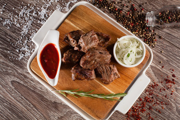 beef kebab on a wooden board in a white dish with pickled onions